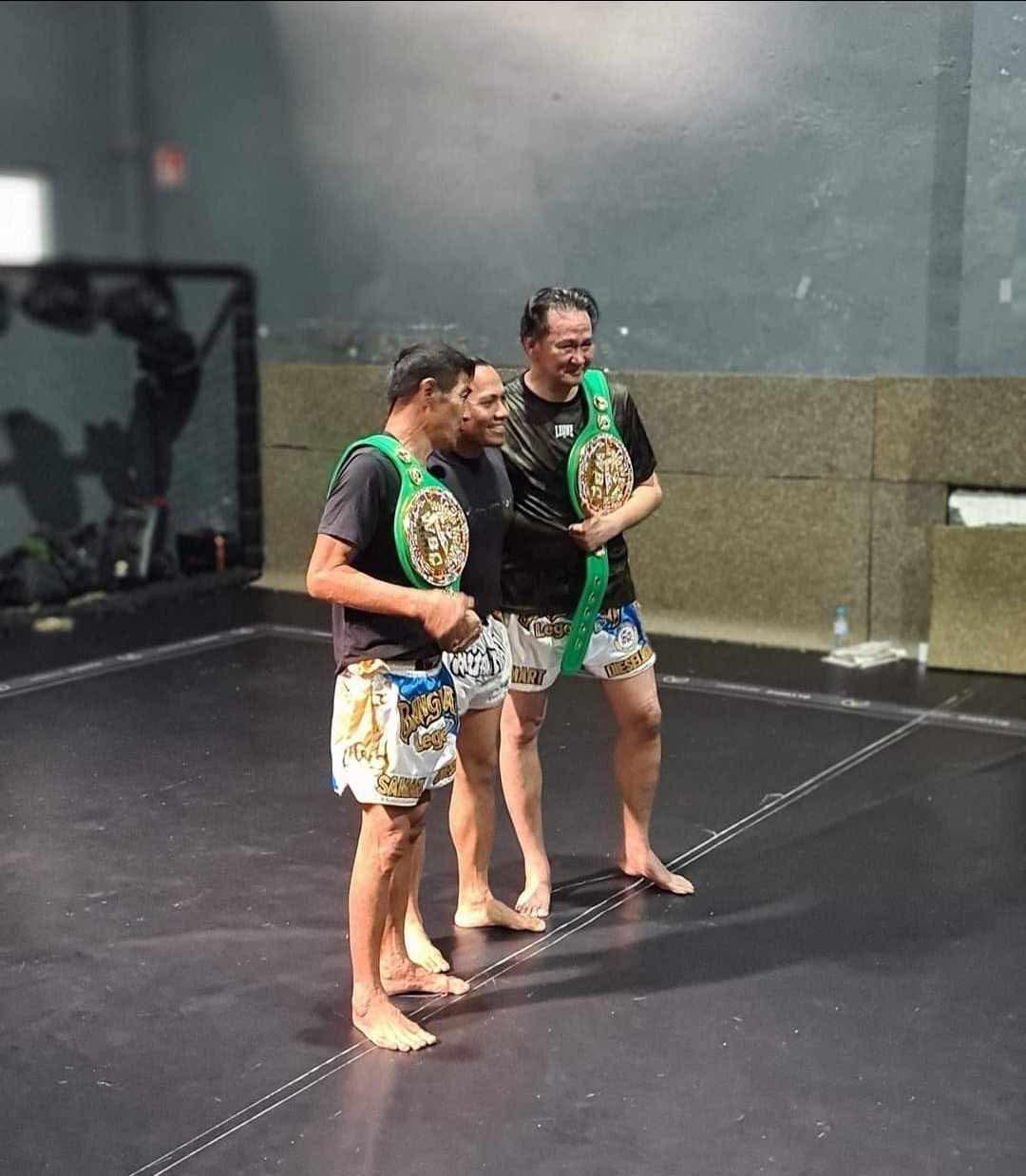 Kru Evert Cubelo con leyendas del Muay Thai y cinturones de campeón